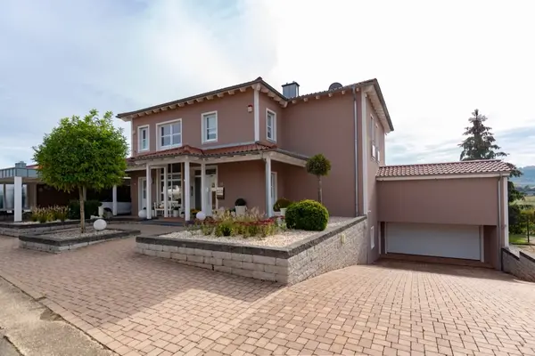 Modernes Einfamilienhaus mit gepflegtem Garten, Doppelgarage und gepflasterter Einfahrt.